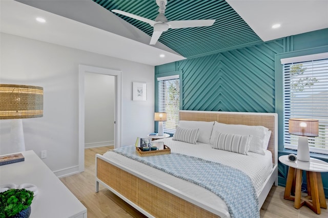 103 4th St N Unit A, Bradenton Beach, FL 34217 - bedroom featuring an accent wall, baseboards, wood finished floors, and a ceiling fan