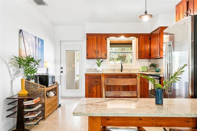 302 Pavonia Rd, Nokomis, FL 34275 - kitchen with stainless steel appliances, a sink, brown cabinets, dark speckled floor, and light stone countertops
