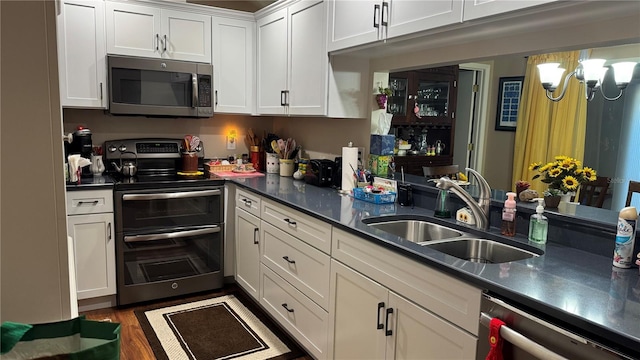 2841 74th St W Unit 2841, Bradenton, FL 34209 - kitchen featuring stainless steel appliances, white cabinets, a chandelier, dark countertops, and wood finished floors
