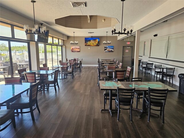 7150 N Tamiami Trl Unit C100, Sarasota, FL 34243 - dining space with dark wood-style flooring, a textured ceiling, a chandelier, and baseboards