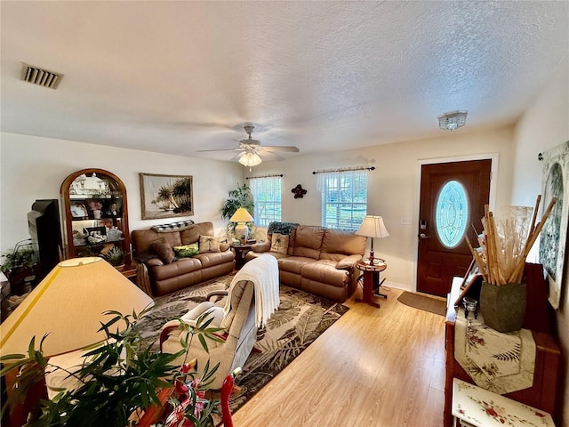 3828 6th Ave W, Palmetto, FL 34221 - living room featuring light wood-type flooring, ceiling fan, a textured ceiling, and baseboards