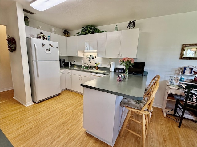 3828 6th Ave W, Palmetto, FL 34221 - kitchen featuring freestanding refrigerator, a peninsula, dark countertops, light wood-style floors, and a sink
