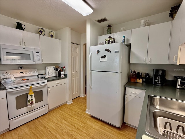 3828 6th Ave W, Palmetto, FL 34221 - kitchen featuring white appliances, dark countertops, light wood-style flooring, and white cabinets