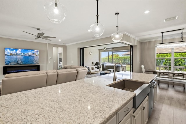 8272 Summer Night Rd, Sarasota, FL 34241 - kitchen featuring a ceiling fan, light stone counters, open floor plan, a sink, and crown molding