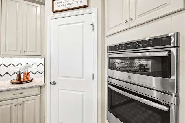 8272 Summer Night Rd, Sarasota, FL 34241 - kitchen featuring stainless steel double oven, white cabinetry, and light stone counters
