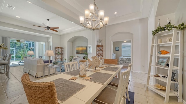 4220 Miriana Way, Sarasota, FL 34233 - dining room featuring arched walkways, a tray ceiling, ceiling fan, light tile patterned floors, and ornamental molding