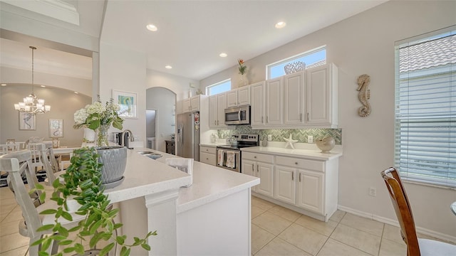 4220 Miriana Way, Sarasota, FL 34233 - kitchen featuring appliances with stainless steel finishes, backsplash, a sink, arched walkways, and light tile patterned floors