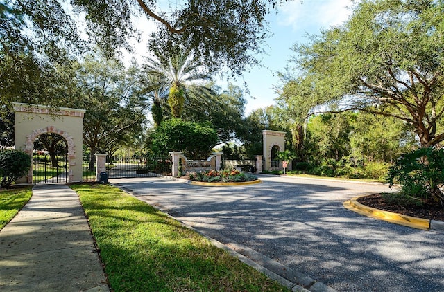 4220 Miriana Way, Sarasota, FL 34233 - view of asphalt road featuring a gate, curbs, a gated entry, and sidewalks