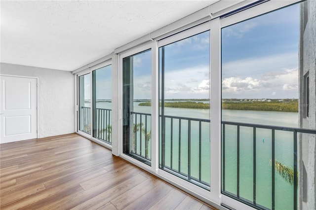 9393 Midnight Pass Rd Unit 603, Sarasota, FL 34242 - unfurnished sunroom with a water view, healthy amount of natural light, and wood finished floors