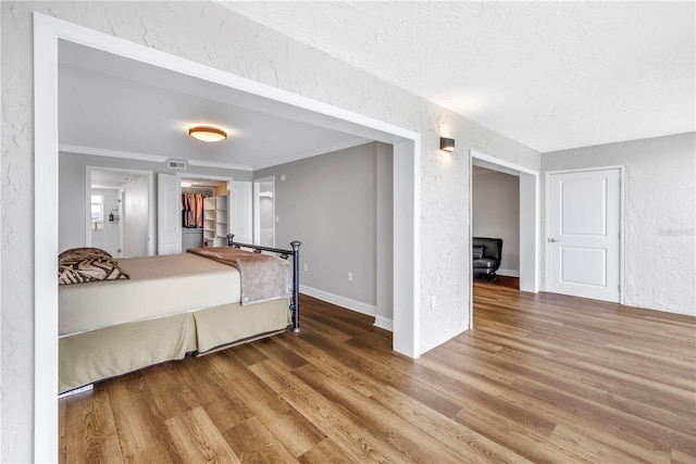 9393 Midnight Pass Rd Unit 603, Sarasota, FL 34242 - bedroom with wood finished floors, a textured wall, a textured ceiling, ornamental molding, and a walk in closet