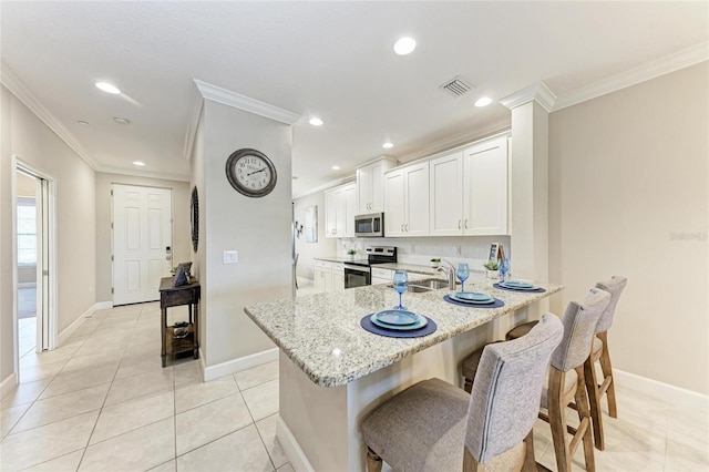 13711 Messina Loop Unit 102, Lakewood Ranch, FL 34211 - kitchen featuring appliances with stainless steel finishes, ornamental molding, light stone counters, baseboards, and light tile patterned flooring