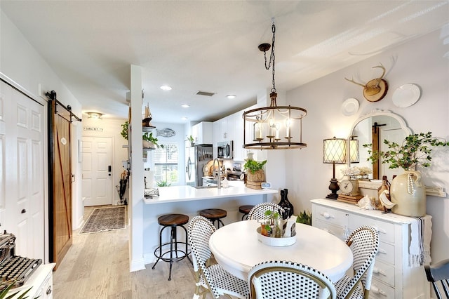 4727 Sabal Key Dr Unit 4727, Bradenton, FL 34203 - kitchen featuring a barn door, appliances with stainless steel finishes, light wood finished floors, white cabinets, and light countertops