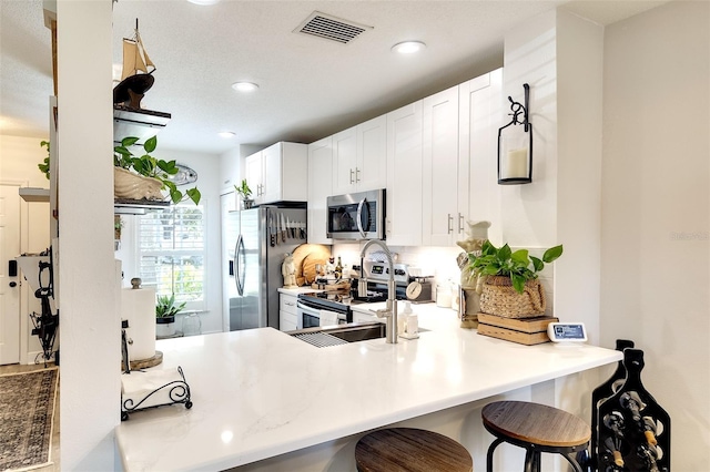 4727 Sabal Key Dr Unit 4727, Bradenton, FL 34203 - kitchen featuring stainless steel appliances, recessed lighting, a peninsula, a kitchen breakfast bar, and white cabinets