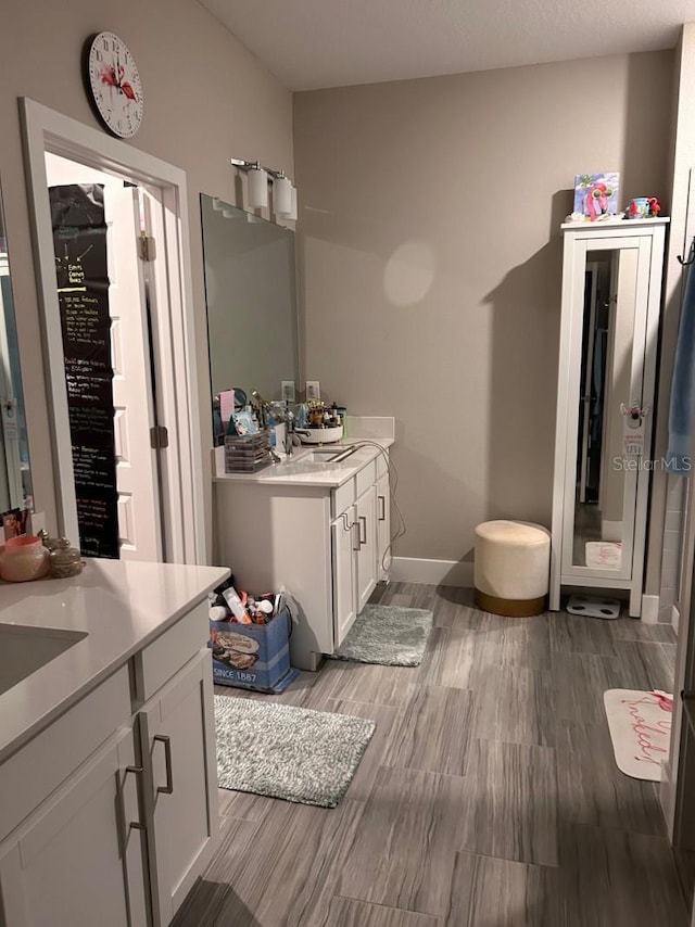 9808 Campanula Ct, Land O Lakes, FL 34637 - bathroom with two vanities, wood finished floors, and baseboards