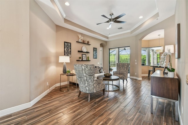 16246 26th St E, Parrish, FL 34219 - sitting room with a ceiling fan, arched walkways, a tray ceiling, baseboards, and dark wood-type flooring