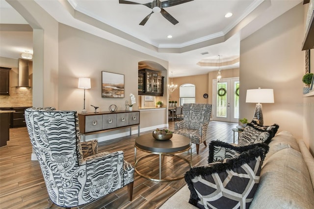 16246 26th St E, Parrish, FL 34219 - living area featuring wood finished floors, ceiling fan, a tray ceiling, arched walkways, and crown molding