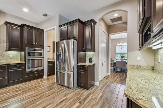 16246 26th St E, Parrish, FL 34219 - kitchen featuring appliances with stainless steel finishes, backsplash, light wood-style floors, dark brown cabinets, and recessed lighting