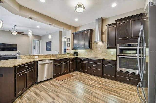 16246 26th St E, Parrish, FL 34219 - kitchen featuring appliances with stainless steel finishes, wall chimney range hood, dark brown cabinets, a peninsula, and light stone counters