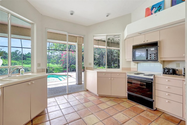3388 Highlands Bridge Rd, Sarasota, FL 34235 - kitchen featuring black microwave, electric stove, a sink, light countertops, and light tile patterned floors