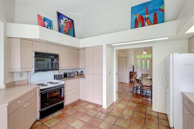 3388 Highlands Bridge Rd, Sarasota, FL 34235 - kitchen with black microwave, range with electric stovetop, freestanding refrigerator, light countertops, and a high ceiling