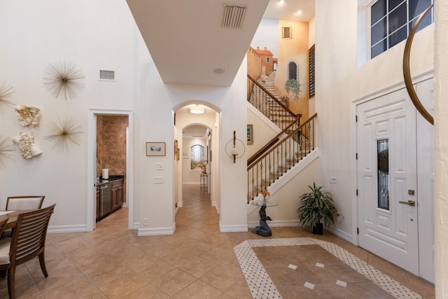 801 3rd St E, Palmetto, FL 34221 - entrance foyer with a towering ceiling, arched walkways, light tile patterned flooring, baseboards, and stairway