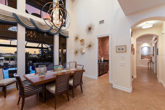 801 3rd St E, Palmetto, FL 34221 - dining space with arched walkways, light tile patterned floors, a towering ceiling, a chandelier, and baseboards