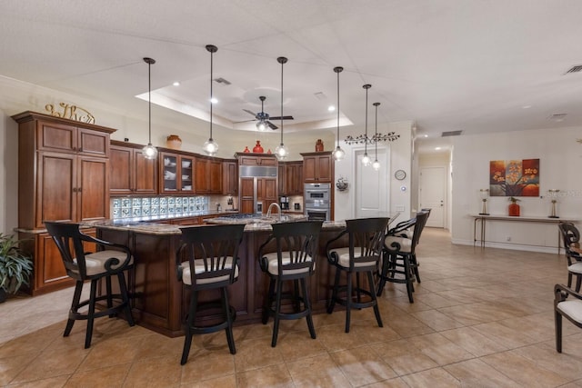 801 3rd St E, Palmetto, FL 34221 - kitchen with stainless steel double oven, ceiling fan, a large island with sink, paneled built in fridge, and decorative light fixtures