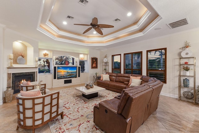 801 3rd St E, Palmetto, FL 34221 - living room with ornamental molding, a fireplace, a ceiling fan, a tray ceiling, and light tile patterned flooring