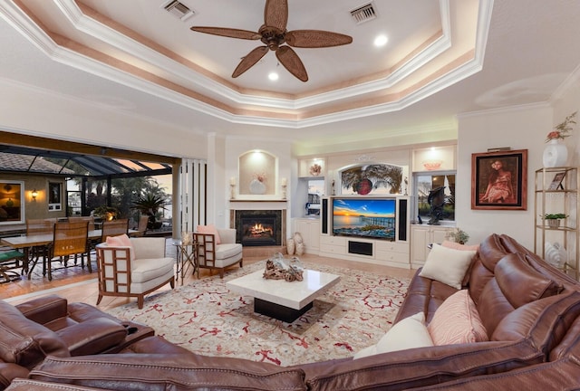 801 3rd St E, Palmetto, FL 34221 - living area featuring ornamental molding, a raised ceiling, ceiling fan, a warm lit fireplace, and wood finished floors
