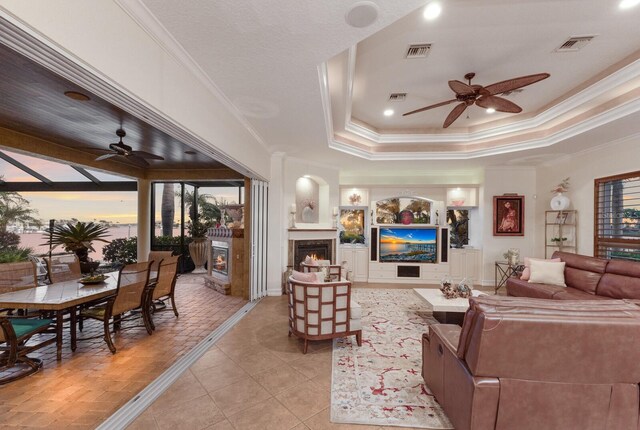 801 3rd St E, Palmetto, FL 34221 - living area with a ceiling fan, a lit fireplace, crown molding, light tile patterned floors, and a raised ceiling