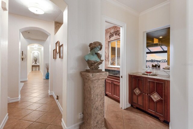 801 3rd St E, Palmetto, FL 34221 - hall with arched walkways, light tile patterned flooring, baseboards, and crown molding