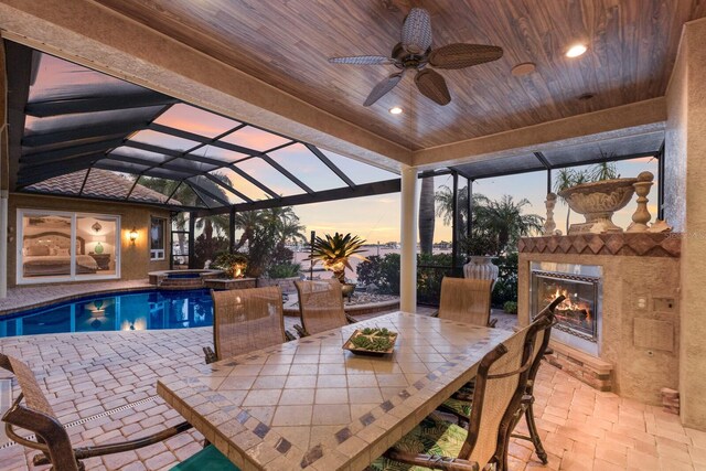 801 3rd St E, Palmetto, FL 34221 - pool at dusk featuring a lit fireplace, a patio, a ceiling fan, and outdoor dining area