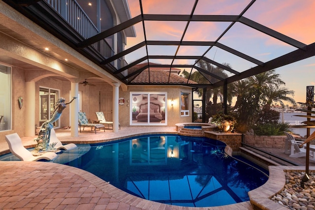 801 3rd St E, Palmetto, FL 34221 - pool at dusk featuring a patio, a pool with connected hot tub, ceiling fan, and a lanai
