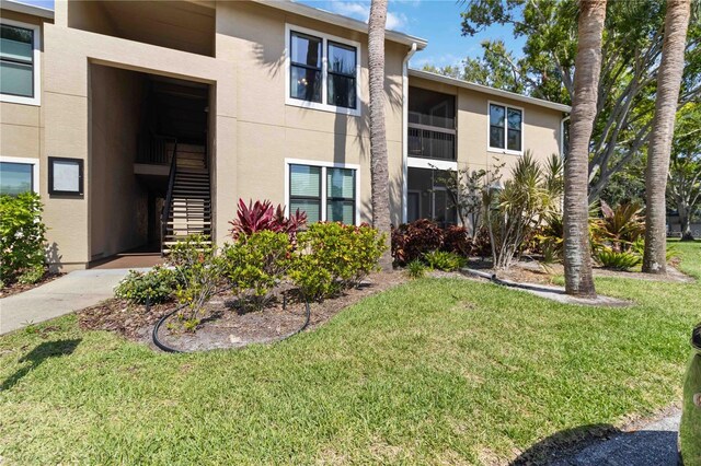 4061 Crockers Lake Blvd Unit 27, Sarasota, FL 34238 - view of front facade featuring stairway, stucco siding, and a front lawn