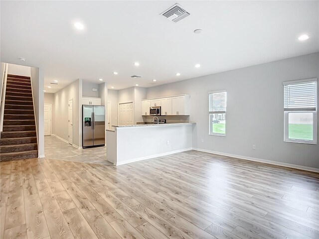 1053 Grantham Dr, Sarasota, FL 34234 - kitchen featuring stainless steel appliances, light wood-type flooring, white cabinets, a peninsula, and recessed lighting