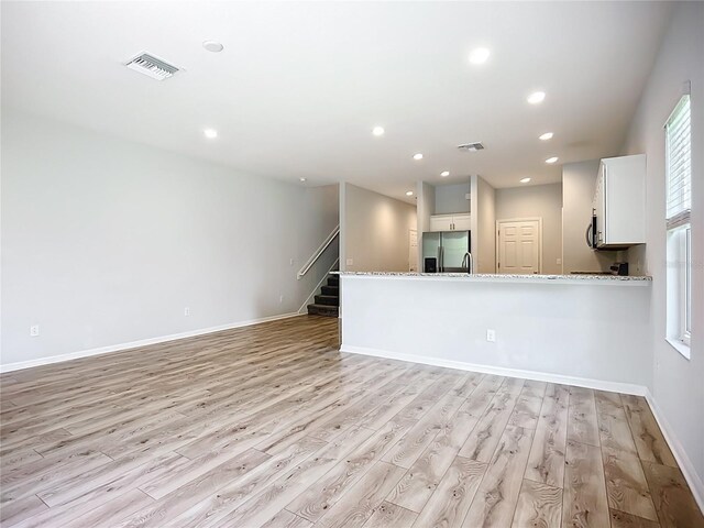 1053 Grantham Dr, Sarasota, FL 34234 - unfurnished living room featuring light wood-style flooring, baseboards, stairway, and recessed lighting