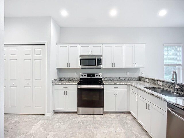 1053 Grantham Dr, Sarasota, FL 34234 - kitchen with stainless steel appliances, a sink, white cabinetry, light stone counters, and recessed lighting