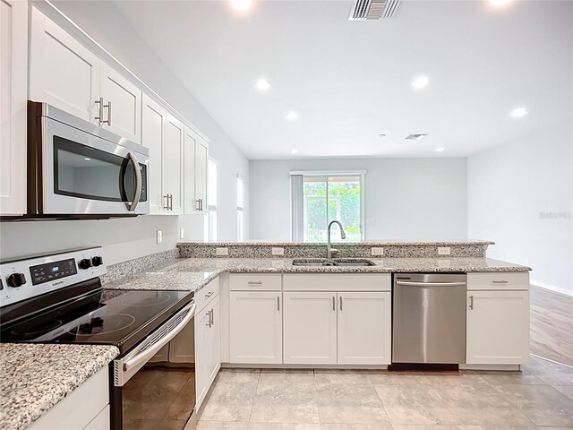 1053 Grantham Dr, Sarasota, FL 34234 - kitchen featuring stainless steel appliances, a sink, white cabinetry, light stone counters, and recessed lighting