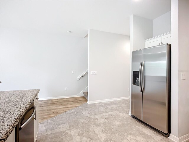 1053 Grantham Dr, Sarasota, FL 34234 - kitchen with stainless steel appliances, white cabinetry, baseboards, and light stone counters