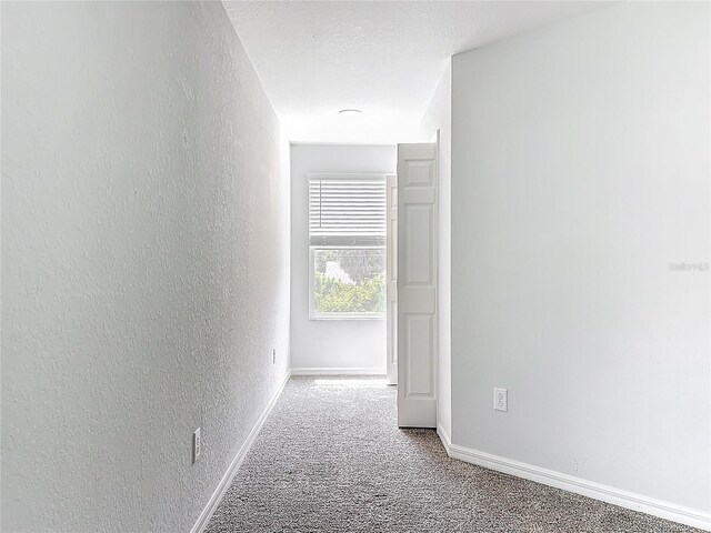 1053 Grantham Dr, Sarasota, FL 34234 - hallway featuring carpet floors, a textured wall, and baseboards