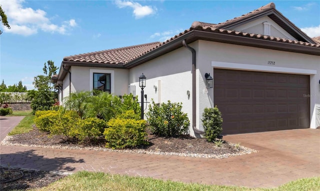 15752 Sacile Ln, Bradenton, FL 34211 - view of property exterior featuring a garage, stucco siding, a tiled roof, and driveway