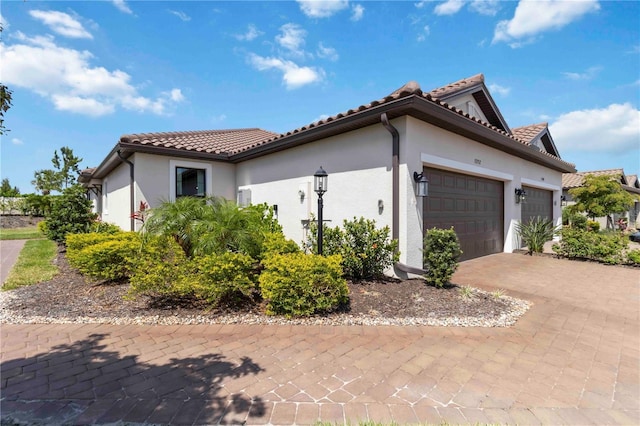 15752 Sacile Ln, Bradenton, FL 34211 - view of property exterior with a garage, decorative driveway, stucco siding, and a tile roof