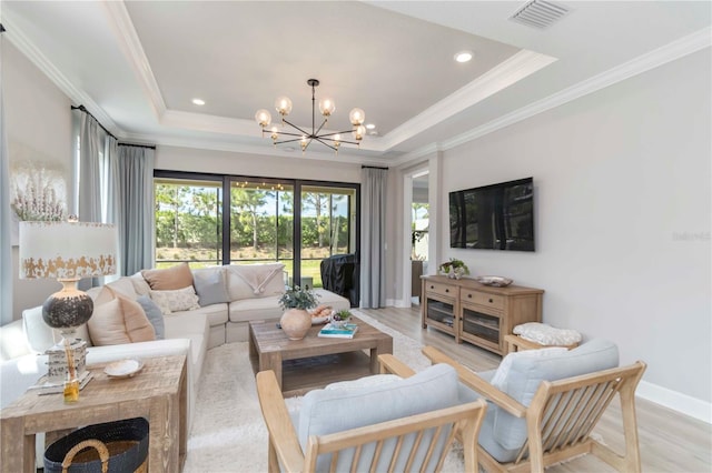 15752 Sacile Ln, Bradenton, FL 34211 - living room featuring light wood finished floors, a chandelier, baseboards, a raised ceiling, and ornamental molding