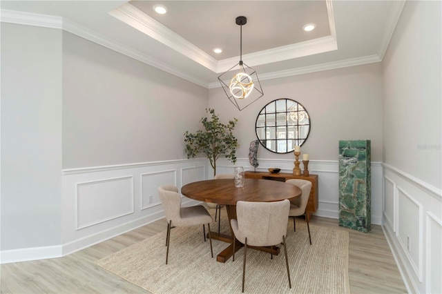 15752 Sacile Ln, Bradenton, FL 34211 - dining area with light wood-style flooring, a chandelier, a raised ceiling, crown molding, and a wainscoted wall