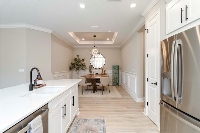 15752 Sacile Ln, Bradenton, FL 34211 - kitchen with stainless steel appliances, a sink, light wood-style floors, hanging light fixtures, and white cabinetry