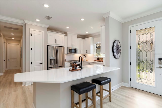 15752 Sacile Ln, Bradenton, FL 34211 - kitchen with appliances with stainless steel finishes, a breakfast bar area, light wood-style floors, baseboards, and crown molding