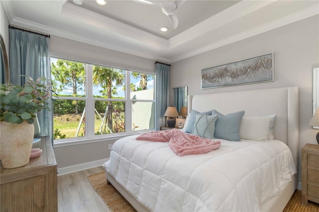 15752 Sacile Ln, Bradenton, FL 34211 - bedroom with multiple windows, ornamental molding, a raised ceiling, light wood-style flooring, and baseboards