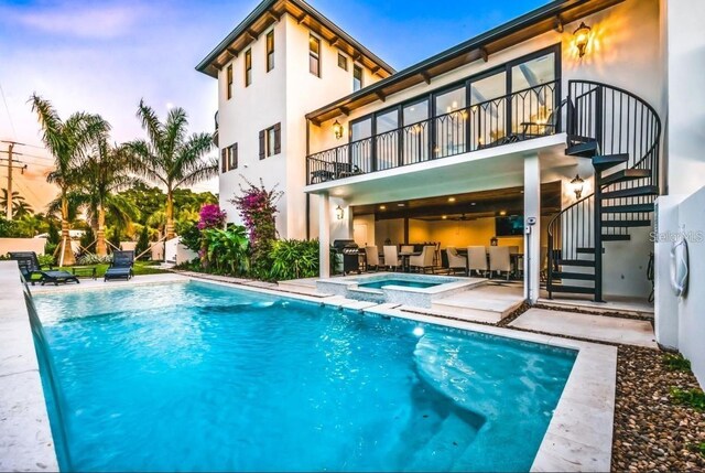340 Jackson Dr, Sarasota, FL 34236 - back of property at dusk with stairway, stucco siding, a patio, a pool with connected hot tub, and a balcony
