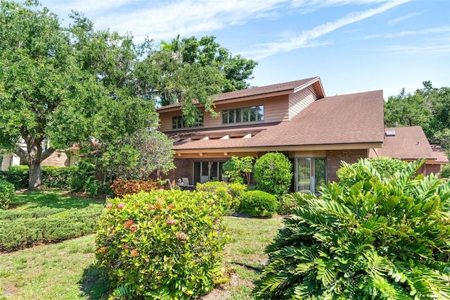 1671 S Dr, Sarasota, FL 34239 - view of front of house with brick siding, a shingled roof, and a front lawn