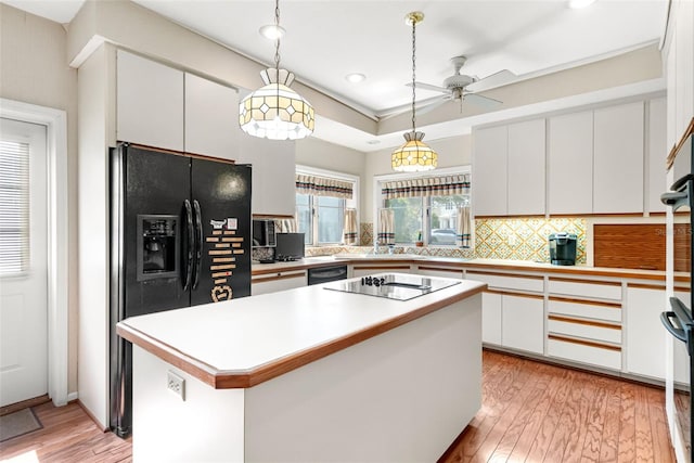 1671 S Dr, Sarasota, FL 34239 - kitchen with black appliances, light wood-style floors, decorative backsplash, ceiling fan, and white cabinetry